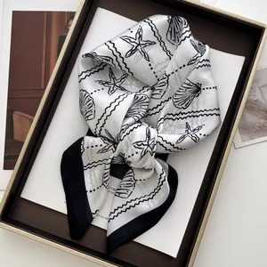 Detail of seashell and starfish print silk scarf displayed in a brown golden tray