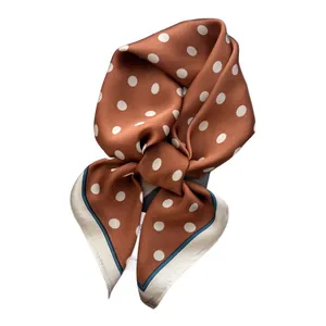 Caramel silk scarf with white polka dots and dark green trim in a bow fold shape