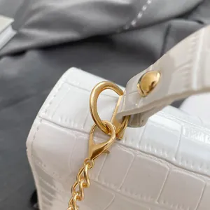 White crocodile-embossed jelly bag with gold chain hardware and glossy finish