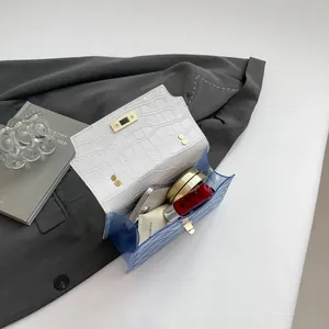 Blue translucent jelly bag with white crocodile pattern flap and gold clasp on a blazer