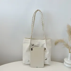 Chique beige draagtas met zilveren vlinders en gevlochten handvat met een tablet