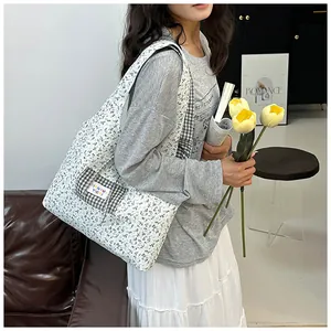 Close-up of floral canvas tote bag featuring a checkered pocket and woven brand label