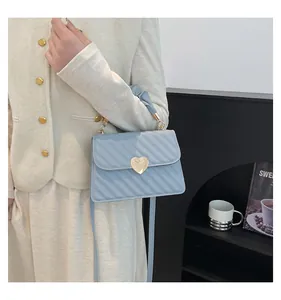 Detail of light blue quilted handbag featuring a gold heart buckle and pleated handle