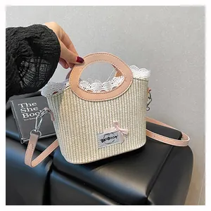 Détail du sac en paille avec bordure dentelle, anses roses et logo noeud élégant