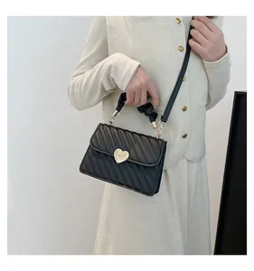 Detail of black quilted handbag with a golden heart clasp and stylish ruched handle