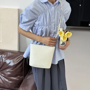 Sac seau blanc tressé minimaliste pour femme porté avec une tenue d'été