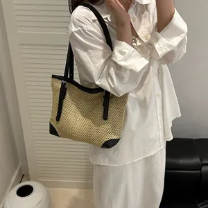 Contrast straw tote bag with black leather straps and metal buckle shown on a model