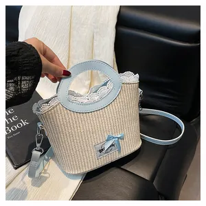 Détail du sac en paille avec bordure en dentelle blanche et nœud en cuir bleu clair