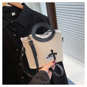 Detail of beige straw handbag with black leather handles and delicate lace edge trim