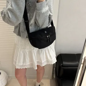 Sac bandoulière en nylon noir imperméable porté avec sweat-shirt gris et jupe en dentelle