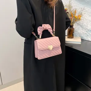 Pink quilted PU leather handbag with gold heart clasp and pleated cloud handle shown on model