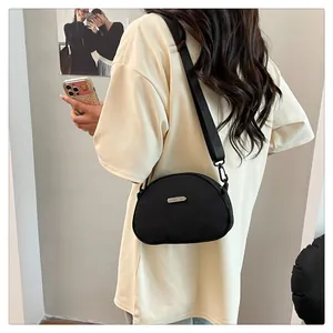 Model wearing a black crescent nylon crossbody bag with adjustable wide strap for daily use