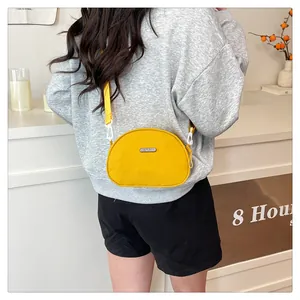 Detail showing the adjustable nylon shoulder strap and shell-shaped yellow crossbody bag