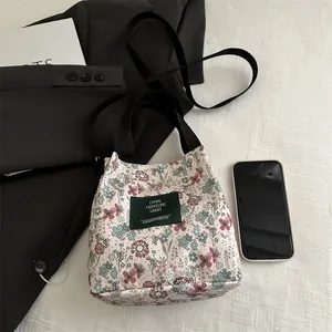 Sac seau en toile à fleurs avec bandoulière noire et poignée pour un look décontracté