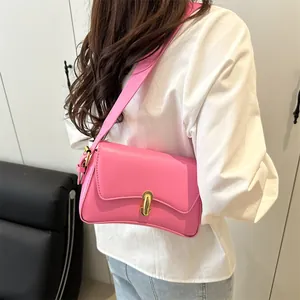 Pink minimalist shoulder bag with gold capsule lock and wide strap shown on model