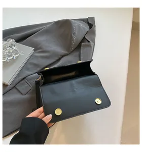 Detail van de open zwarte vierkante tas met binnenvoering en dubbele gouden magneetsluitingen