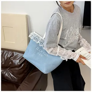Détail d'un sac cabas en toile bleu clair avec bordure en dentelle blanche et texte