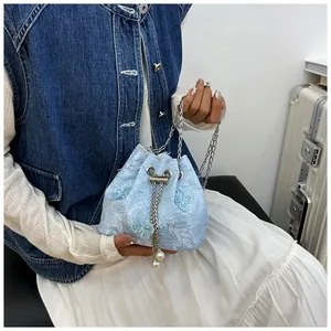 Détail du sac seau bleu clair avec broderie florale et breloques de cordon en perles