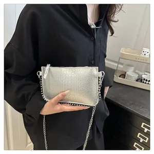 Detail of silver crocodile pattern bag with black studs and metallic chain strap