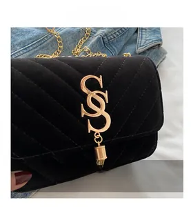 Close-up of black velvet crossbody bag with quilted pattern, gold logo and chain strap