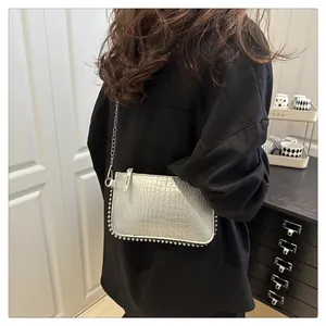 Detail view of silver crocodile embossed shoulder bag with metallic studs and chain strap