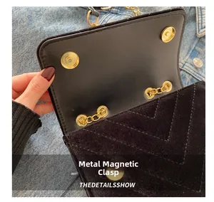 Close-up of golden magnetic snap closure on black quilted velvet handbag with V-stitch