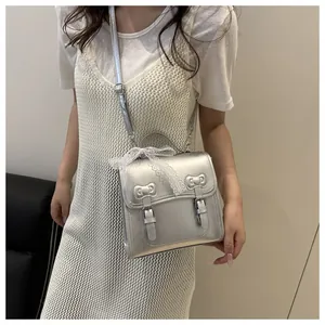 Detailed view of a silver metallic crossbody bag with lace bows and twin buckle straps