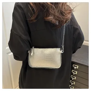 Detailed view of silver crocodile embossed handbag with metal chain and rivet trim