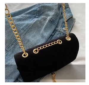 Close-up of quilted black velvet chain bag featuring gold logo and tassel detail