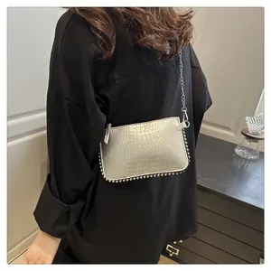 Detail of silver crocodile pattern crossbody bag with beaded edges and metal chain strap