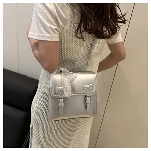 Close-up of silver bow-accented handbag featuring white lace details on the handle