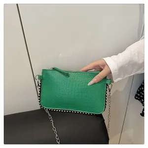 Close-up of green crocodile-patterned shoulder bag featuring silver metal bead trim and chain