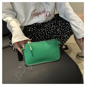 Detail of green crocodile pattern bag with silver bead trim and metal chain strap