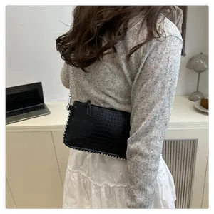 Detail of black crocodile texture shoulder bag with silver rivet trim and chain strap