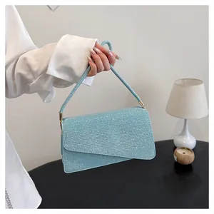 Detail of light blue glitter crossbody bag with asymmetrical flap and gold metal hardware