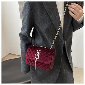 Detail showing Burgundy velvet crossbody bag with V-quilted texture and gold tassel chain