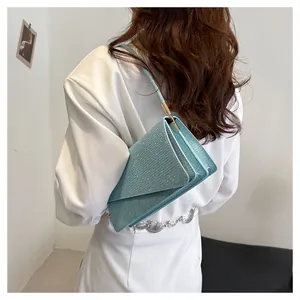 Detail of light blue glitter shoulder bag featuring structured accordion folds and gold hardware