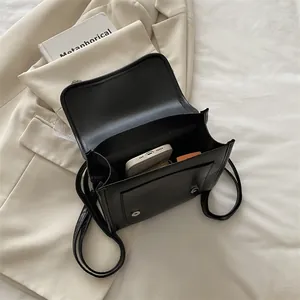 Black leather crossbody bag with magnetic flap showing interior storage and front pocket