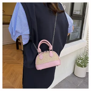 Pink leather and straw patchwork mini shell bag worn on shoulder by model outdoors