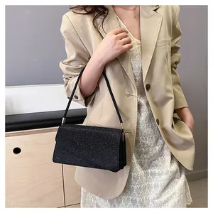 Detail of black sequin underarm bag on model with elegant beige suit and lace skirt