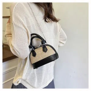 Close-up of shell bag featuring woven fabric and black leather contrast stitching detail