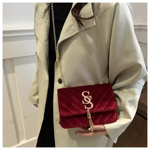 Detail of red velvet crossbody bag featuring V-shaped quilting and gold S-logo tassel