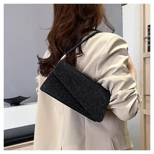Detail of glittery black underarm bag with gold metal buckle on a shoulder strap