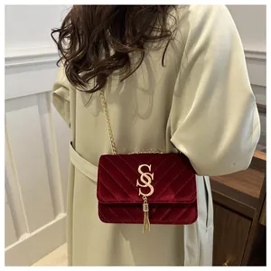 Detail of burgundy chevron velvet bag with gold SS logo and chain strap on shoulder