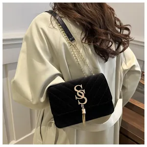 Detail of black velvet crossbody bag with V-shaped quilting and gold fringe logo