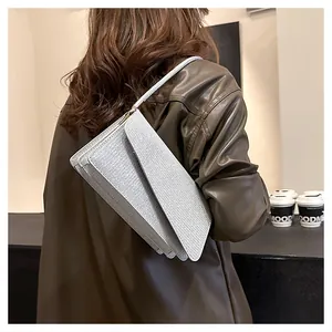 Detail of silver glitter shoulder bag with asymmetric triangular flap on a leather jacket