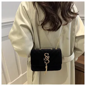 Close-up of black velvet crossbody bag with V-quilted stitching and gold metal tassel