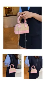 Detail of a woven shell crossbody bag with pink leather trim and metal chain strap