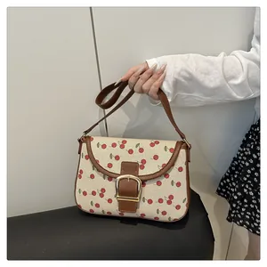 Close-up of cherry print canvas and brown leather strap with gold metal buckle