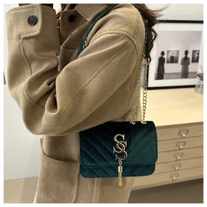 Detailed macro view of dark green velvet bag with V-shaped stitching and golden tassel